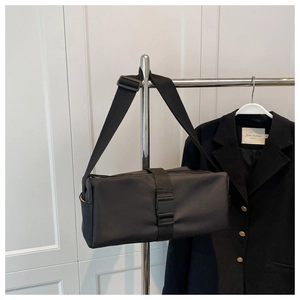 Detail of nylon crossbody bag showing buckle strap, side pocket, and adjustable strap