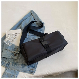 Detail view of a black nylon crossbody bag featuring a clip buckle and wide strap