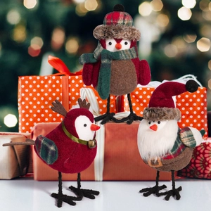 Three cute Christmas bird figurines with Santa hats and scarves on a festive background