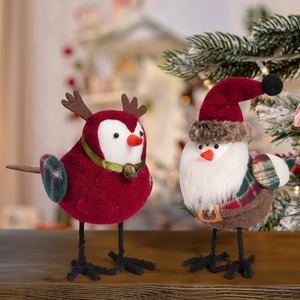 Close-up of bird ornaments with Christmas hats and reindeer antlers on wooden desk