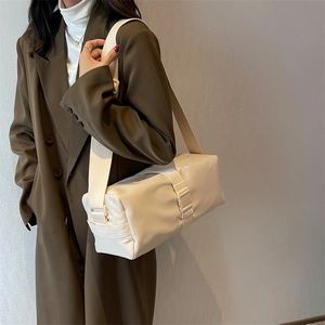 Minimalist beige crossbody bag with wide fabric strap and decorative buckle detail