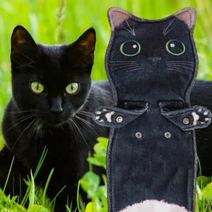 Detail view of a black cat-shaped microfiber towel with embroidery and metal snaps