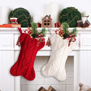 Set of red and white knit bone-shaped Christmas stockings hanging on a white fireplace