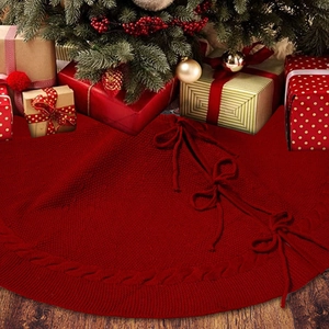 Detail of burgundy knitted Christmas tree skirt with cable weave and bow ties