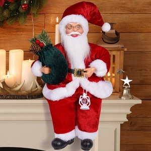Close-up of sitting Santa doll with velvet suit, gift bag and lantern on a fireplace