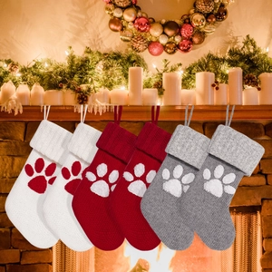 Detail of six knit paw-print Christmas stockings hanging on a festive decorated fireplace