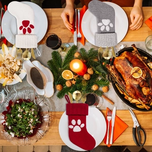 Knitted Christmas pet paw cutlery holders with gold silverware on festive dinner table decor
