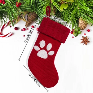 Mini knitted Christmas stocking with white dog paw print and festive holiday decorations