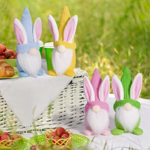 Close-up of four colorful Easter bunny gnomes in a sunny outdoor picnic setting