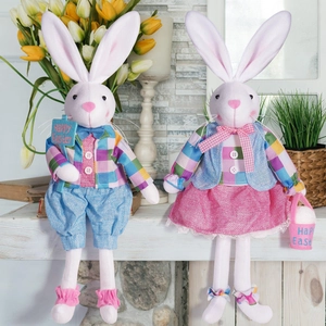Pair of plush Easter bunnies in festive outfits with Happy Easter signs on a mantel