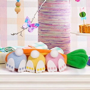Macro detail of plush carrot storage with three colorful bunny plushies for Easter