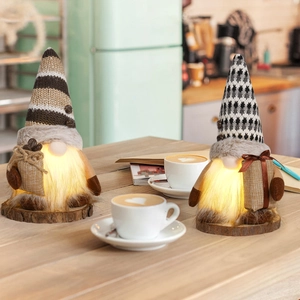 Close-up of lighted coffee gnomes with knitted hats and mini coffee bean bags on table