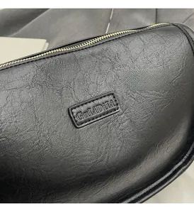 Détail du sac en cuir noir texturé avec fermeture éclair dorée et logo embossé