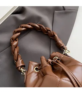 Detail of woven leather handle and quilted texture on brown bucket bag with gold hardware