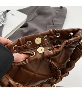 Detail of dark brown quilted leather handbag with gold metal clasp and woven handle