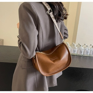 Détail du sac bandoulière en cuir marron foncé avec large sangle tissée ethnique