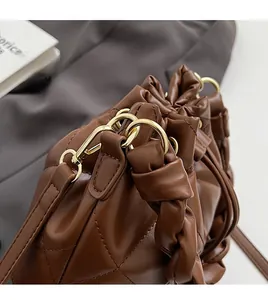Detailed close-up of dark brown quilted bag with gold metal hooks and detachable strap