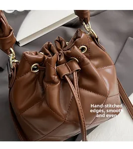 Detail of brown leather bucket bag with quilted stitching and gold hardware rings