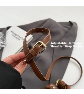 Detail of adjustable dark brown leather shoulder strap with golden metal buckle
