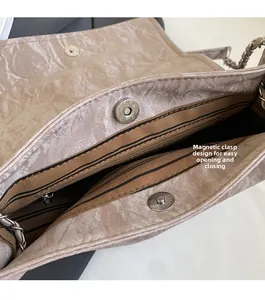 Detail view of beige pleated shoulder bag featuring magnetic buckle and striped lining