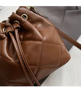 Close-up of dark brown bucket bag featuring quilted diamond pattern and drawstring detail