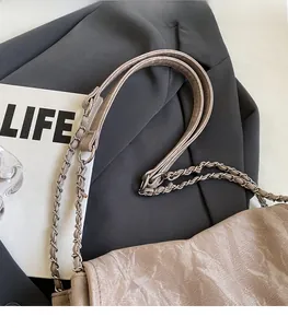 Detail view of beige pleated leather tote bag with elegant chain shoulder strap