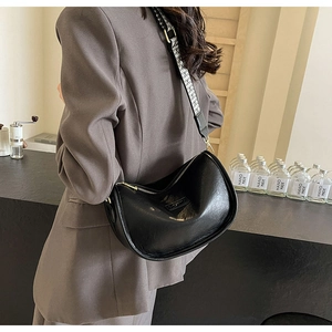 Détail du sac hobo en cuir noir avec bandoulière tissée et finitions métalliques dorées