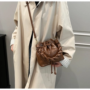 Detail of dark brown quilted leather bucket bag with braided trim and drawstring closure