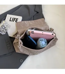 Top view of spacious interior of light brown ruched shoulder bag holding a tablet and phone