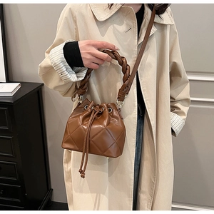 Brown quilted leather bucket bag with woven handle and drawstring closure shown on model