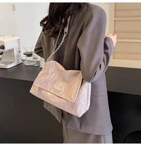 Pink pleated tote bag with silver chain strap worn with a professional brown blazer