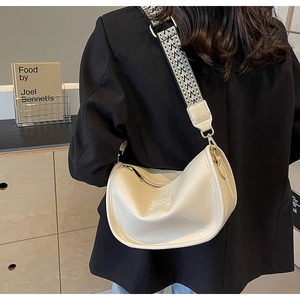 Détail du sac demi-lune blanc cassé avec bandoulière tissée géométrique sur un modèle