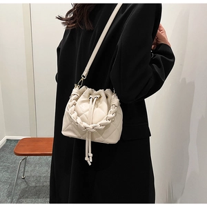 Detail of cream quilted bucket bag with braided handle and adjustable crossbody strap