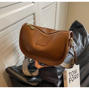 Détail du sac hobo marron avec large bandoulière tissée et texture en cuir litchi