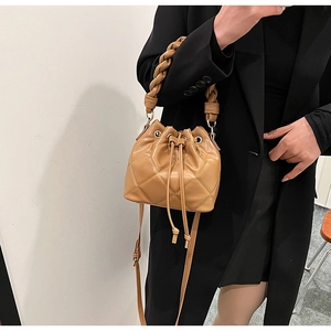 Detail of camel quilted bucket bag showing woven handle and drawstring closure