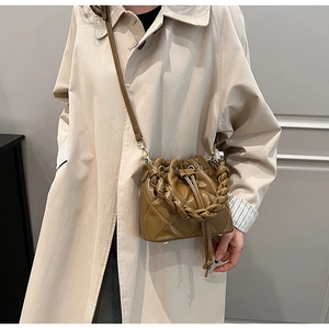 Detail of light brown quilted bucket bag featuring a woven handle and drawstring closure