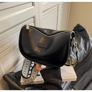 Détail du sac bandoulière demi-lune noir avec large sangle tissée aux motifs géométriques
