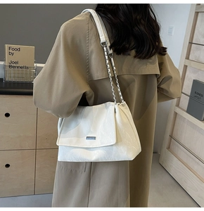 Detail of white tote bag with marble texture and metal chain strap on model shoulder