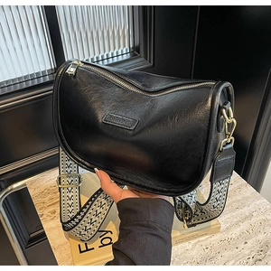 Détail du sac bandoulière noir en cuir texturé avec sangle tissée à motifs géométriques