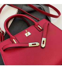 Detail of red wedding handbag featuring litchi grain leather and golden metal hardware