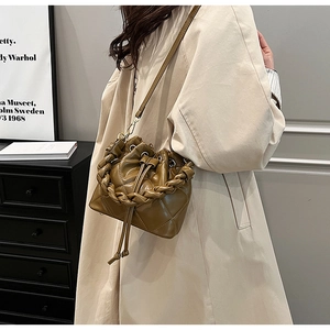 Close-up of brown quilted bucket bag featuring woven handle and drawstring detail
