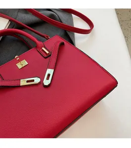 Detailed close-up of red lychee pattern leather handbag with gold metal twist lock buckle