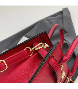 Detailed close-up of premium red pebble leather texture and gold metal hardware on handbag