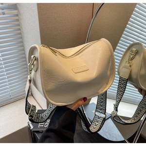 Détail du sac en cuir crème avec large bandoulière géométrique et finitions dorées