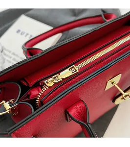 Close-up of red lychee pattern leather handbag featuring gold zipper and metal hardware