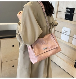 Detail of pink pleated tote bag featuring silver chain strap and metallic accents