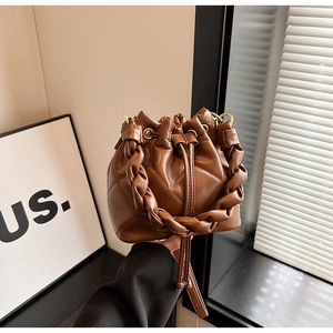 Detailed view of a brown quilted leather bucket bag featuring a woven handle and drawstring