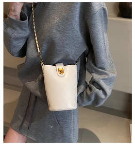 Close-up of white quilted bucket bag featuring a gold chain strap and elegant metal clasp