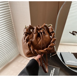 Detail of dark brown quilted bucket bag with woven knot handle and drawstring closure