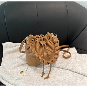 Close-up of brown quilted bucket bag with drawstring closure and woven handle detail